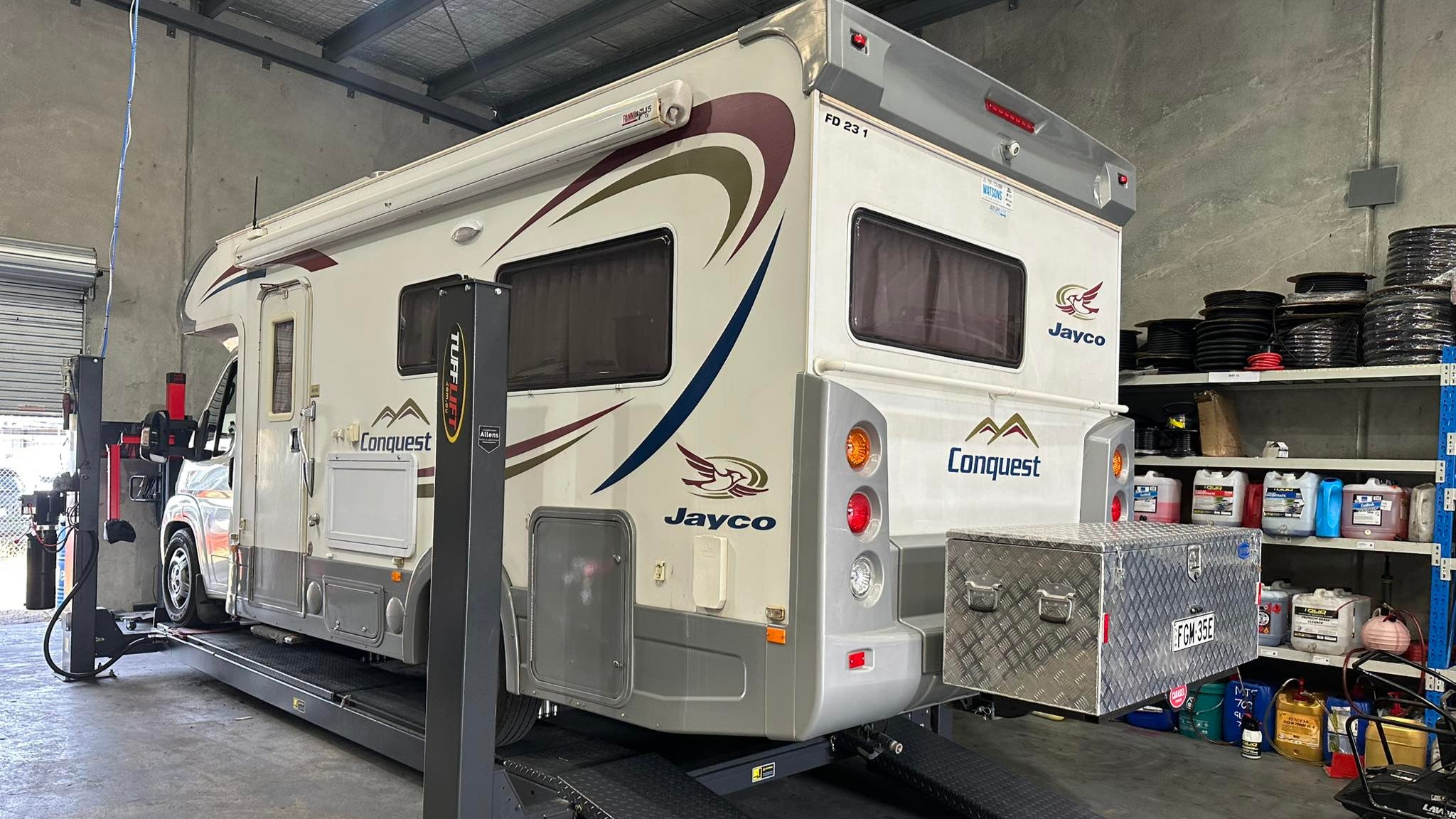 Jayco Conquest travel trailer on a lift in a garage setting